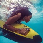 Woman snorkeling underwater with yellow board