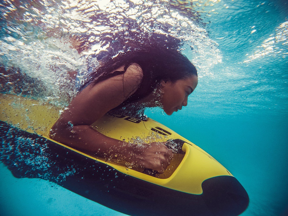 Woman snorkeling underwater with yellow board