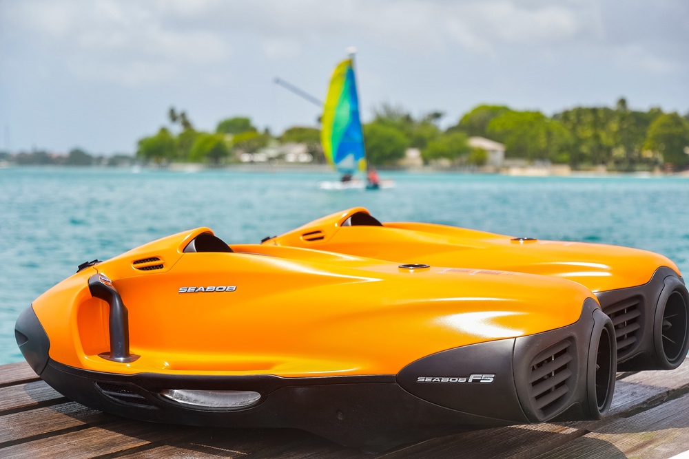 Two orange Seadoo jet skis on a tropical dock