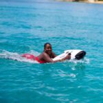 Woman smiling on bodyboard in clear blue ocean