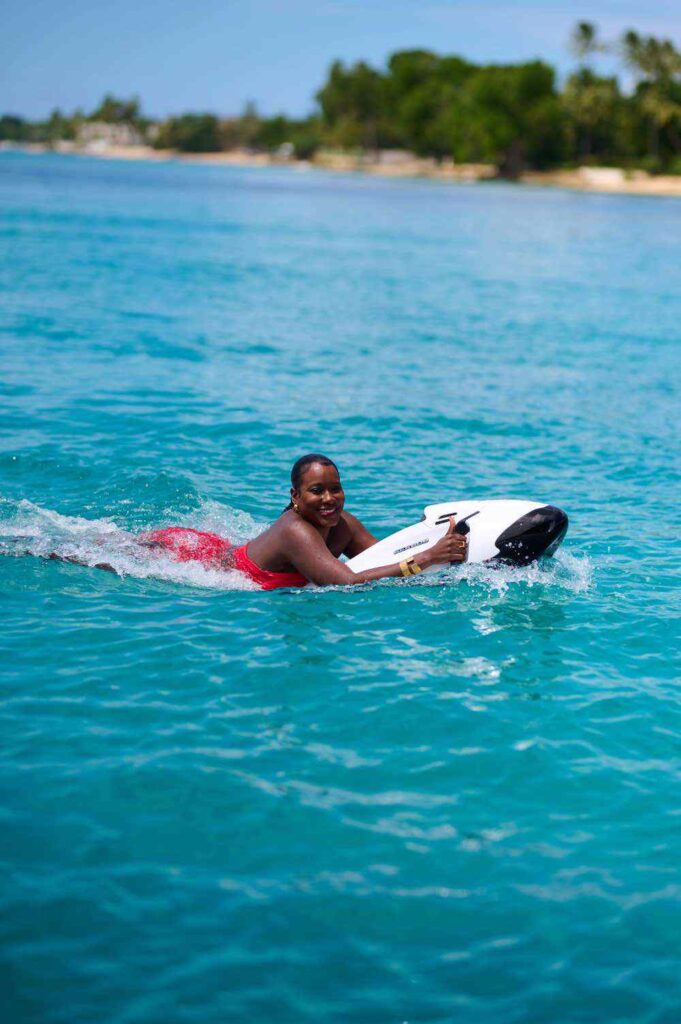 Woman smiling on bodyboard in clear blue ocean