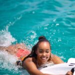 Woman joyfully surfing in clear turquoise water