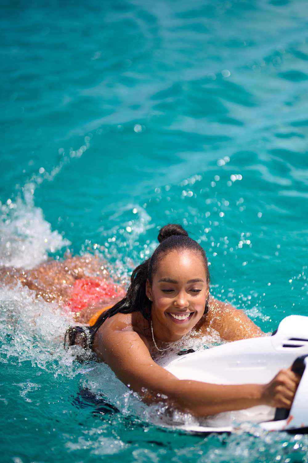 Woman joyfully surfing in clear turquoise water