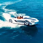 White sports car styled boat rides waves in ocean.