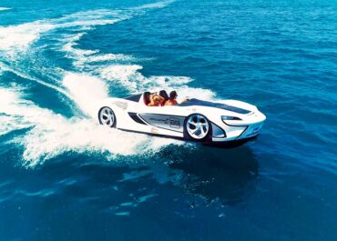 White sports car styled boat rides waves in ocean.