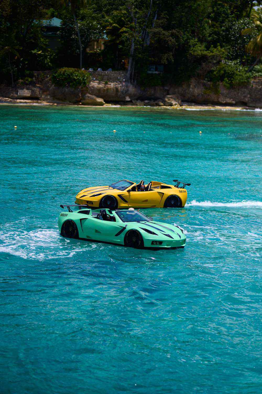 Yellow and green sports cars floating on turquoise sea