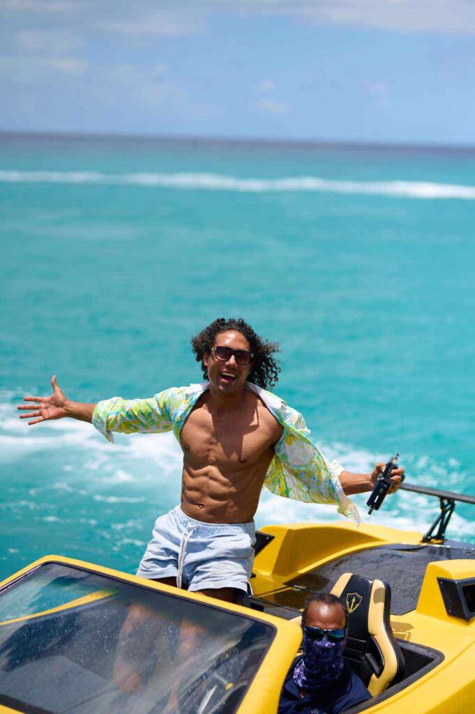 Man joyfully poses on boat in sunny tropical ocean