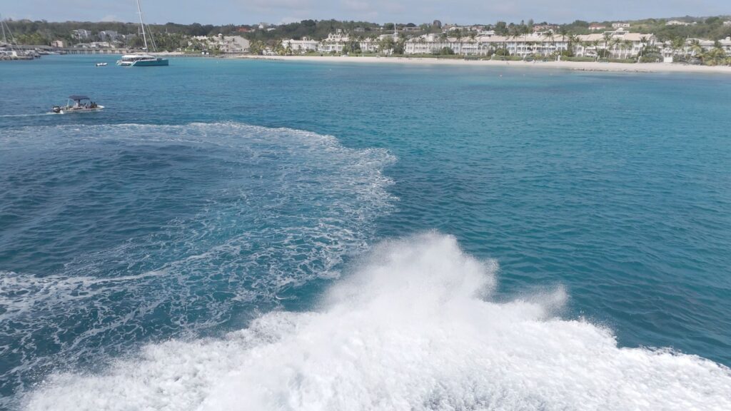 Boat creating wake near tropical coastline
