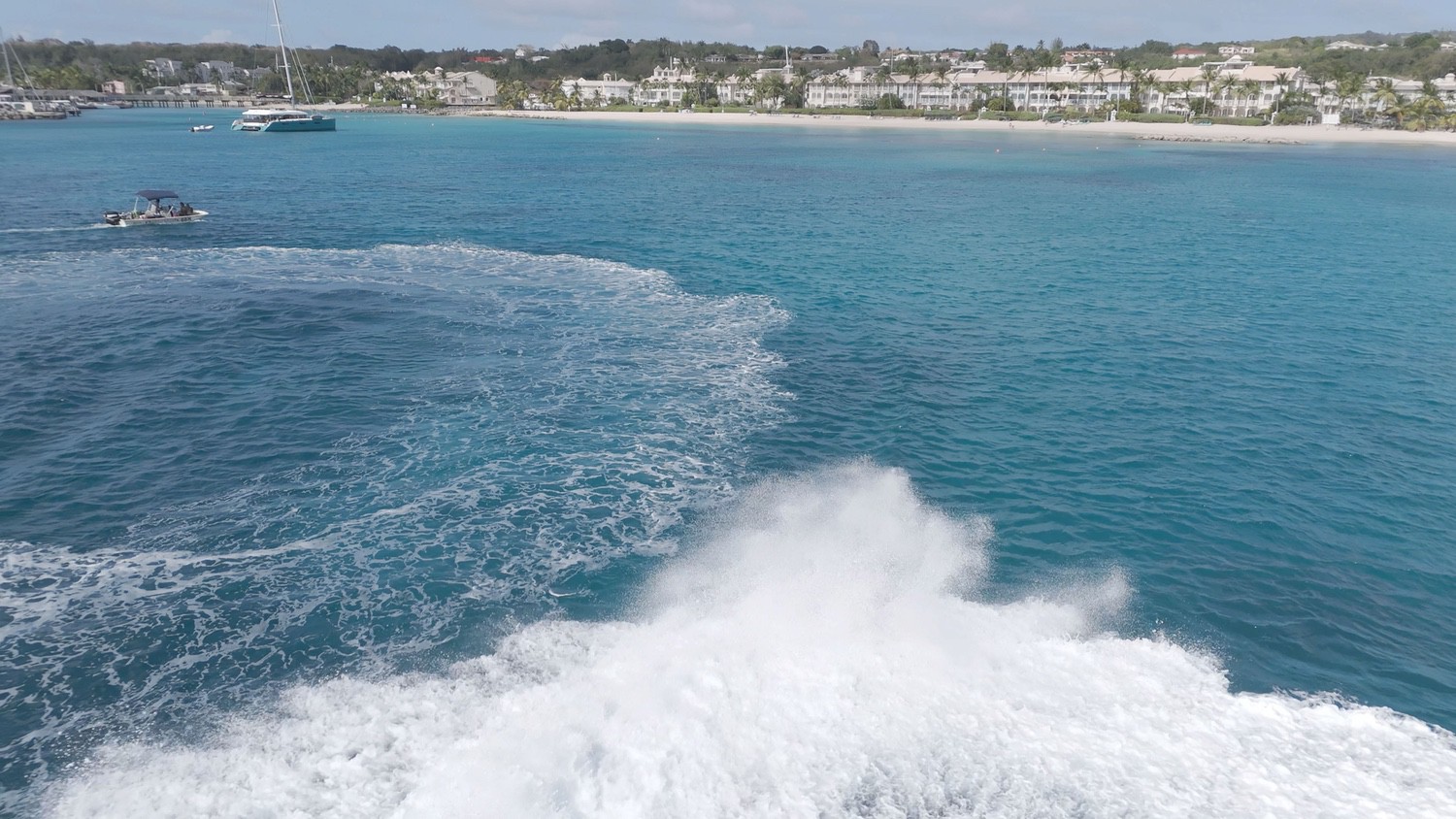 Boat creating wake near tropical coastline