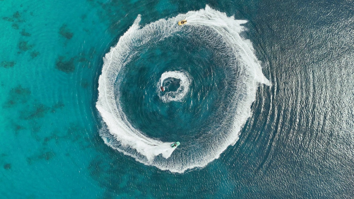 Aerial view of jet skis circling on turquoise water