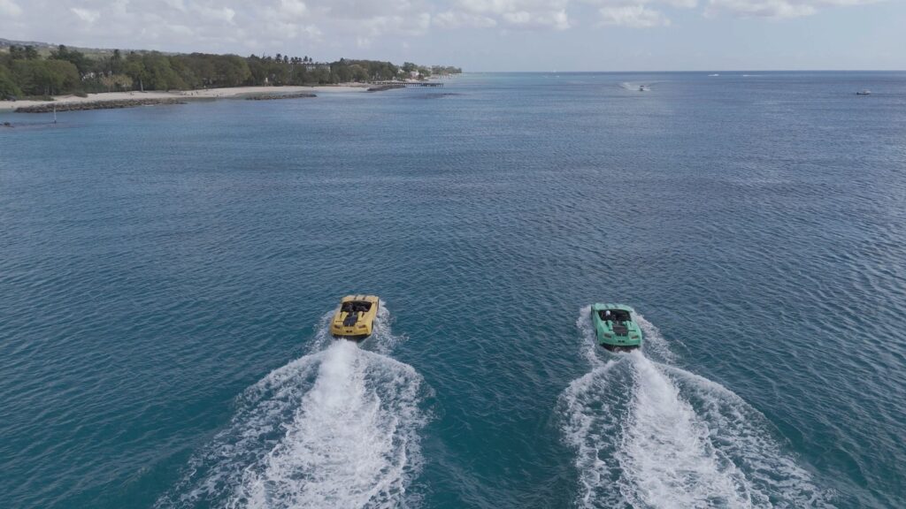 Two boats speeding on clear blue water near coast