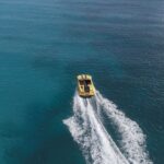 Yellow boat speeding on clear blue ocean