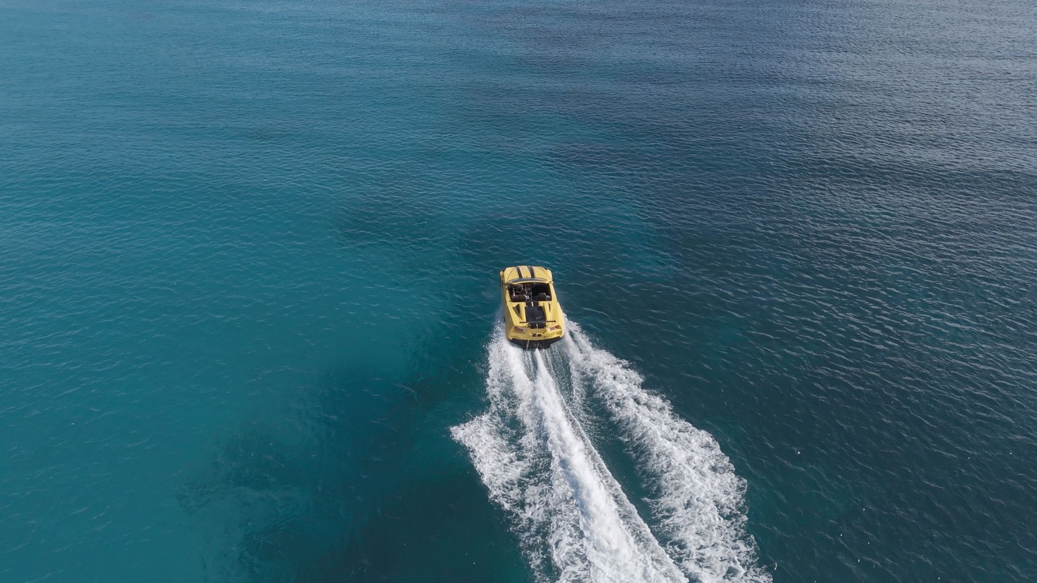 Yellow boat speeding on clear blue ocean